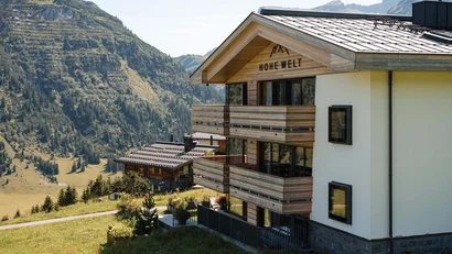 Bergwohnung mit Balkon vor bewaldeten Bergen und Tal