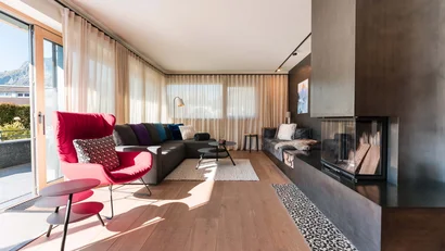 Helles Wohnzimmer mit Kamin, rotem Sessel und großem grauem Sofa