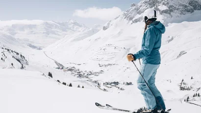 Skifahrerin blickt auf verschneites Tal und Berglandschaft