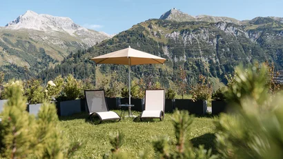 Zwei Liegestühle mit Sonnenschirm in Garten mit Bergblick
