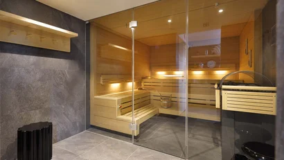 Moderne Sauna mit Holzliegen hinter einer gläsernen Tür