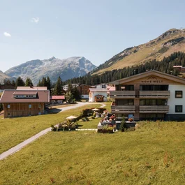 Alpenlandschaft mit Häusern, grünen Wiesen und Bergen im Hintergrund