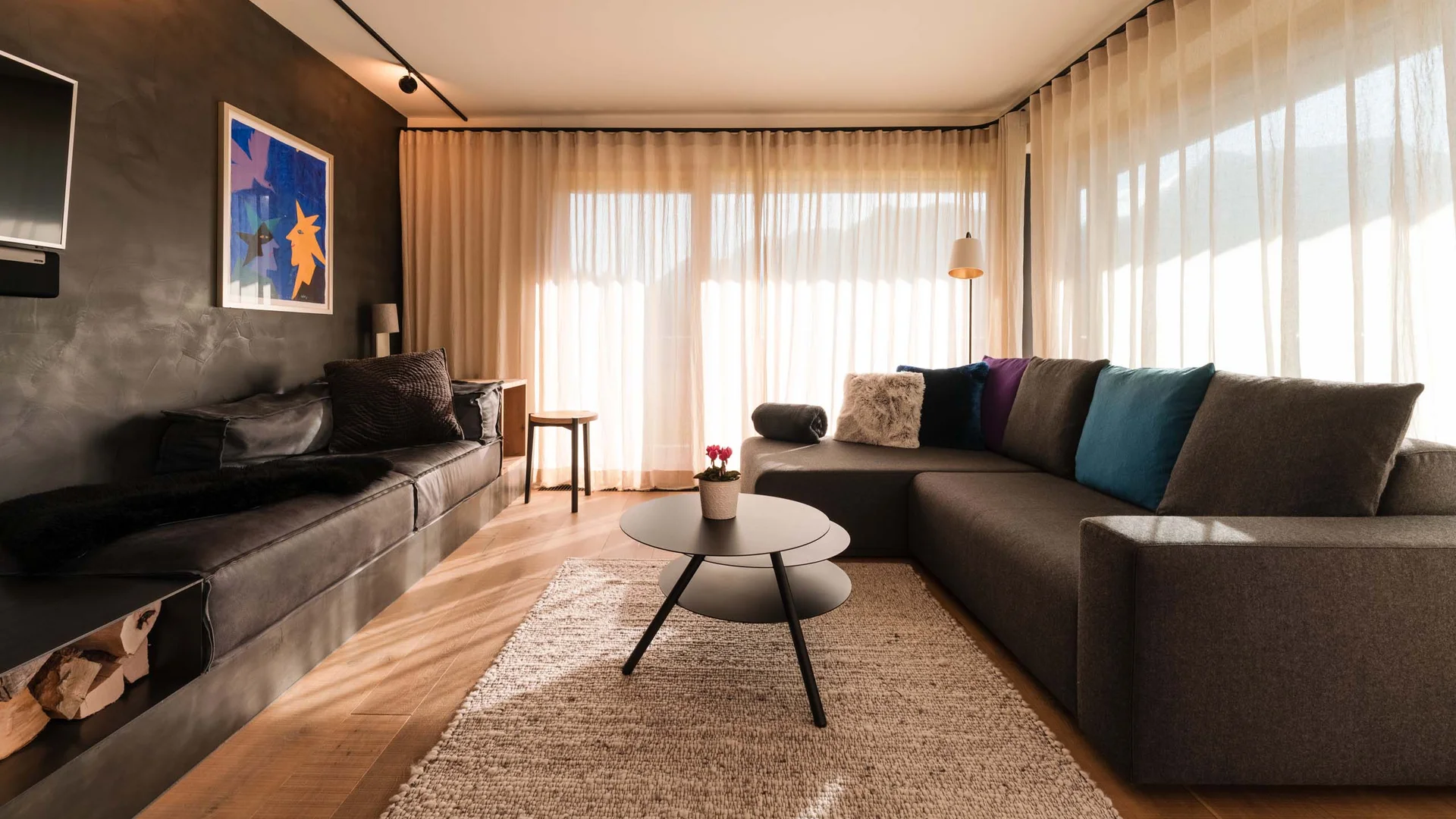 Modernes Wohnzimmer mit Sofa, Couchtisch und großen Fenstern mit Vorhängen