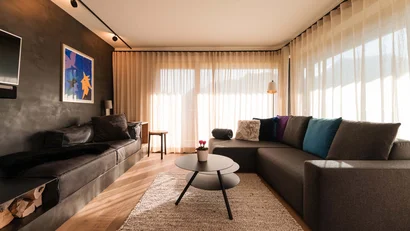 Modernes Wohnzimmer mit Sofa, Couchtisch und großen Fenstern mit Vorhängen