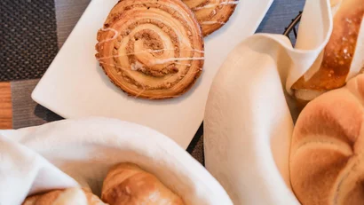 Zimtgebäck und verschiedene Brötchen in weißen Servietten auf einem Tisch