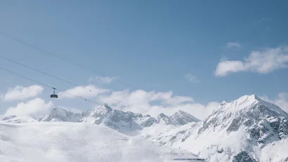Seilbahn über schneebedeckte Berge unter blauem Himmel