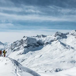 Zwei Snowboarder auf schneebedecktem Berg mit Alpen im Hintergrund