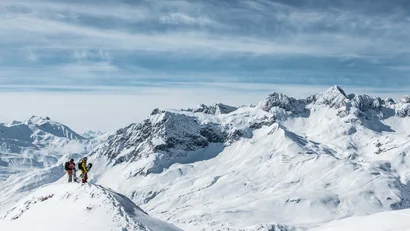 Zwei Snowboarder auf schneebedecktem Berg mit Alpen im Hintergrund