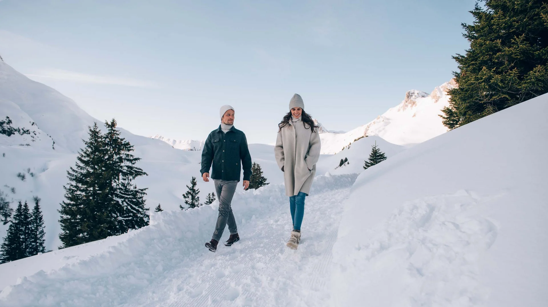 Zwei Menschen wandern durch eine verschneite Berglandschaft