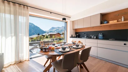 Moderne Küche mit Frühstückstisch und Bergblick durch großes Fenster