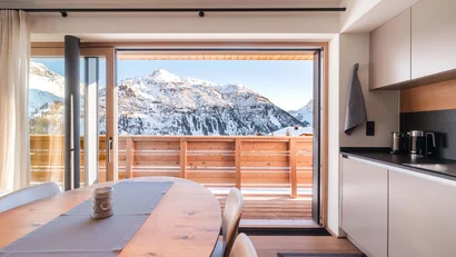 Essbereich mit Küche und Balkon mit Blick auf verschneite Berggipfel