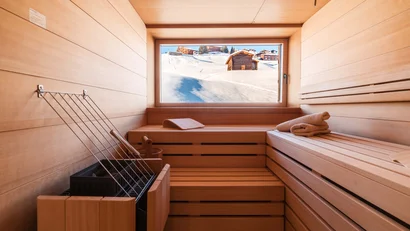 Holzsauna mit Blick auf eine verschneite Berglandschaft