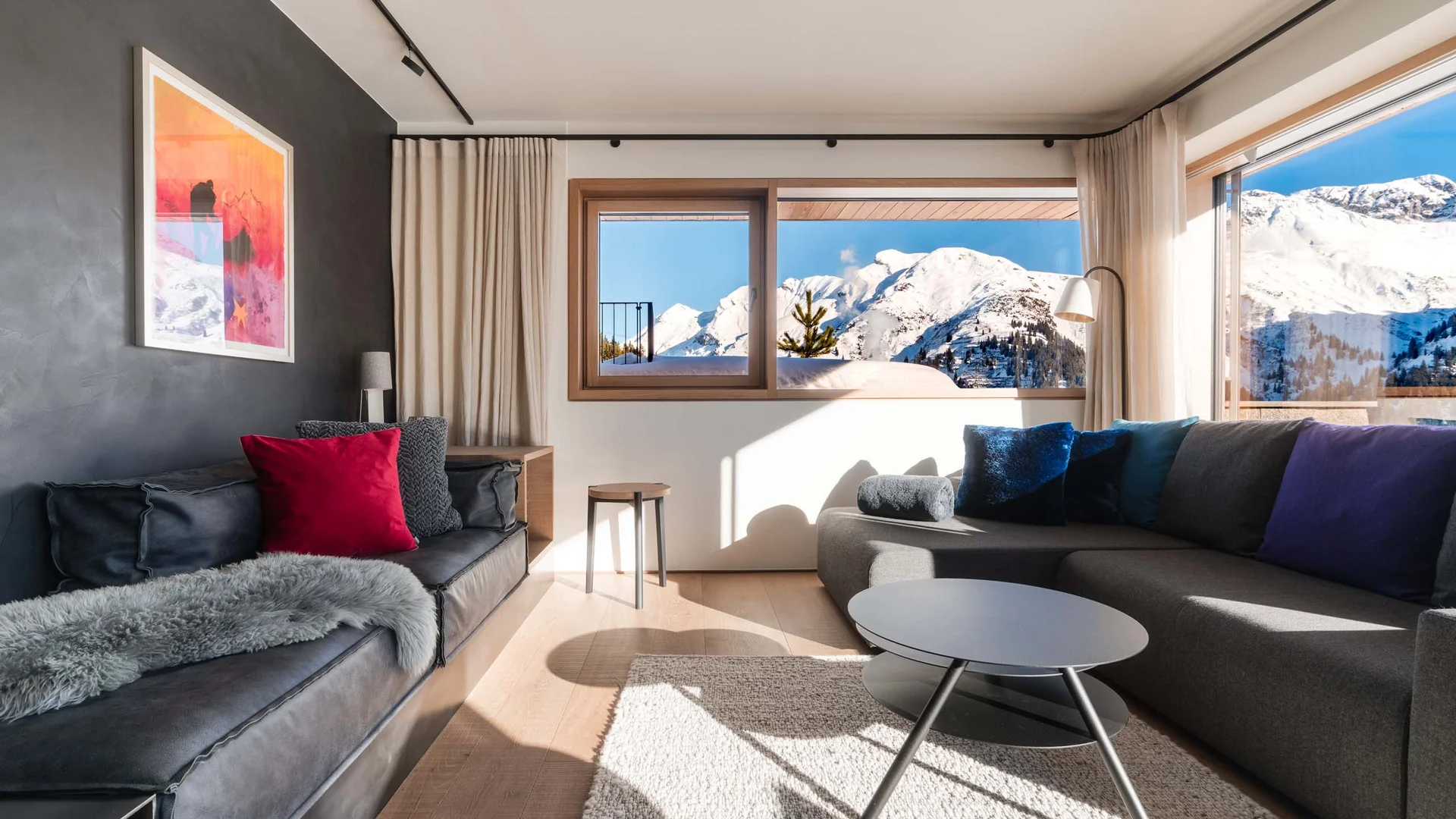 Modernes Wohnzimmer mit Sofas, Couchtisch und verschneitem Bergblick
