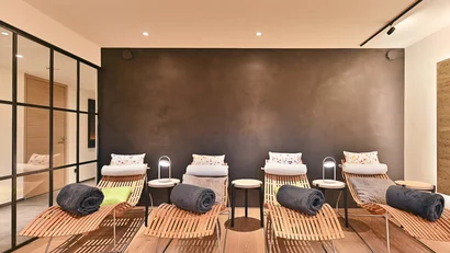 Ruhebereich mit Holzliegen und Handtüchern in modernem Wellnessraum