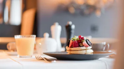 Pfannkuchen mit frischen Beeren und Saftglas auf Tisch gedeckt