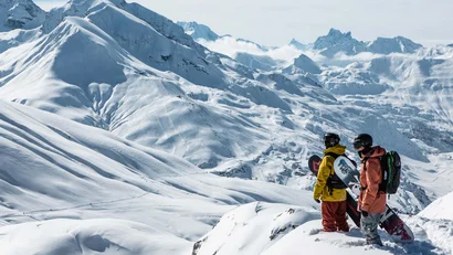 Zwei Snowboarder blicken auf verschneite Berglandschaft