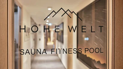 Glastür mit Hohe-Welt-Logo und Hinweis auf Sauna, Fitness und Pool