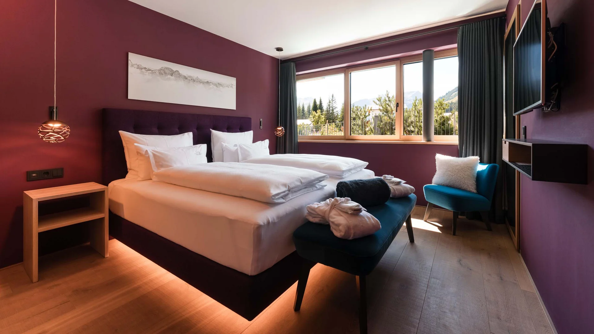 Modernes Schlafzimmer mit lila Wänden, gemütlichem Bett und Bergblick